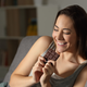 Actual title: “Happy woman eating chocolate in the night”
